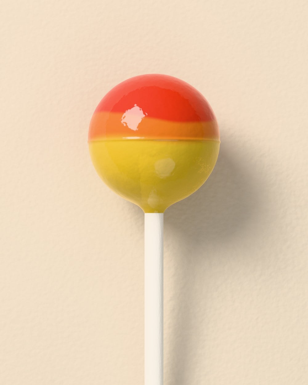 The same stick, now with a glossy round hard candy on top, red at the crown fading to yellow.